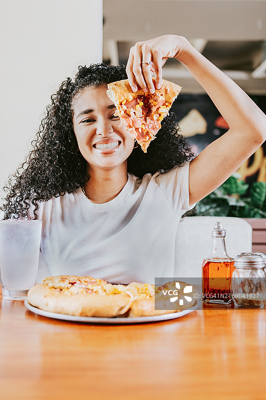 在餐厅享用披萨的非洲裔女子，展示披萨切片图片素材