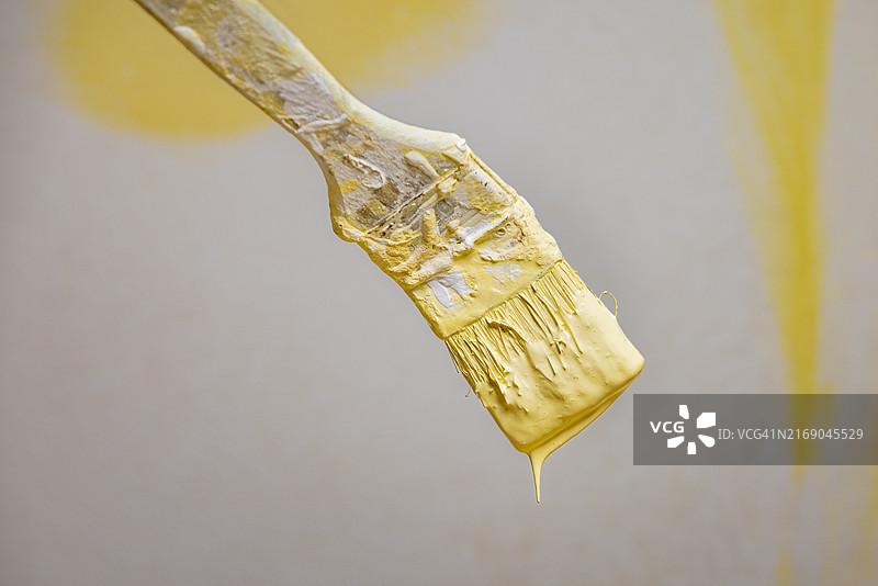 未完成油漆墙前的黄色油漆刷图片素材