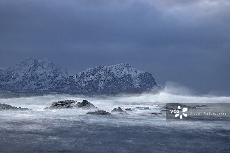 飓风席卷冰冷的北冰洋，在韦斯特拉伦群岛的雪山前掀起巨浪图片素材
