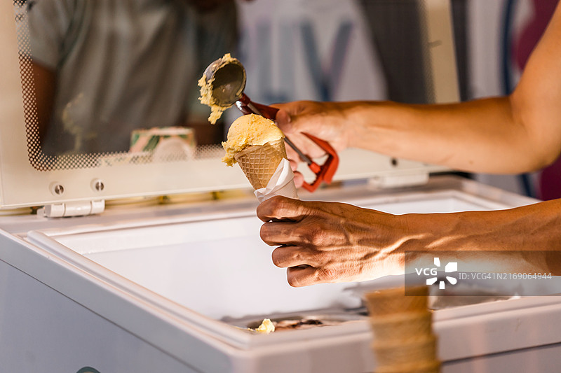 冰淇淋销售员将冰淇淋放入蛋卷筒中图片素材