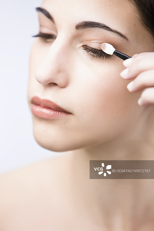 年轻女子涂眼影的侧面特写图片素材