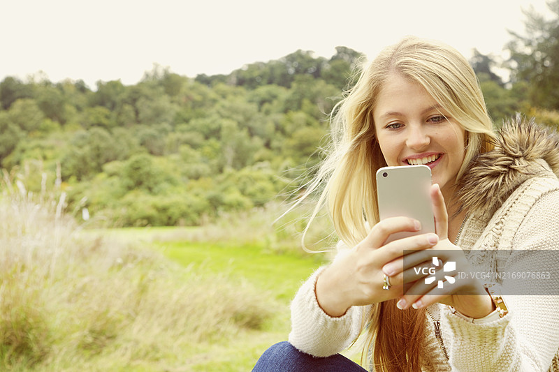 年轻女人田野中使用智能手机图片素材