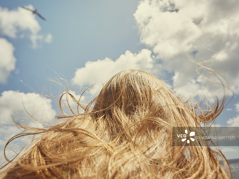 阳光明媚的夏日天空下的长发少女仰视角度图片素材