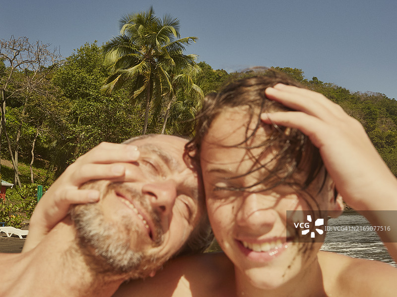 圣文森特和格林纳丁斯：阳光沙滩上开怀大笑拥抱的快乐父子图片素材