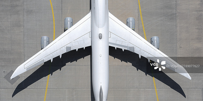 俯视：阳光明媚的机场停机坪上的白色飞机图片素材