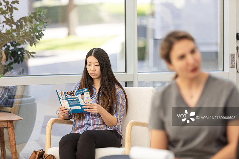 严肃的女人在诊所候诊室阅读宣传册图片素材