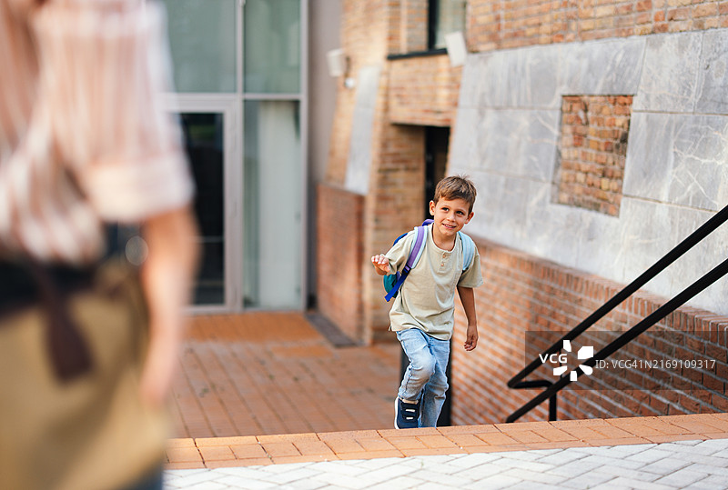 男孩兴高采烈地背着书包返回学校图片素材