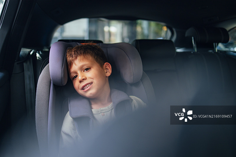 坐在汽车座椅上准备返校的微笑男孩图片素材
