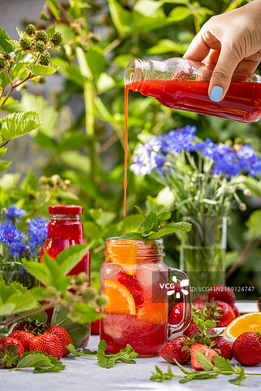 女人在桌子上往玻璃杯里倒饮料的裁剪图图片素材