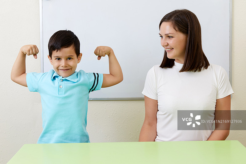 男孩向老师展示手臂肌肉图片素材