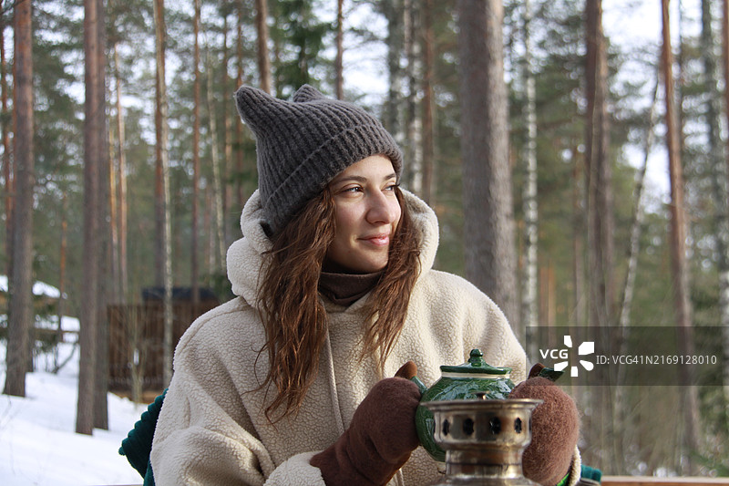 年轻女子坐在冬季森林的桌旁眺望远方图片素材