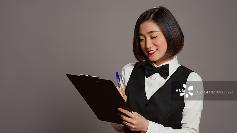 年轻女子手持书本，背景为灰色图片素材