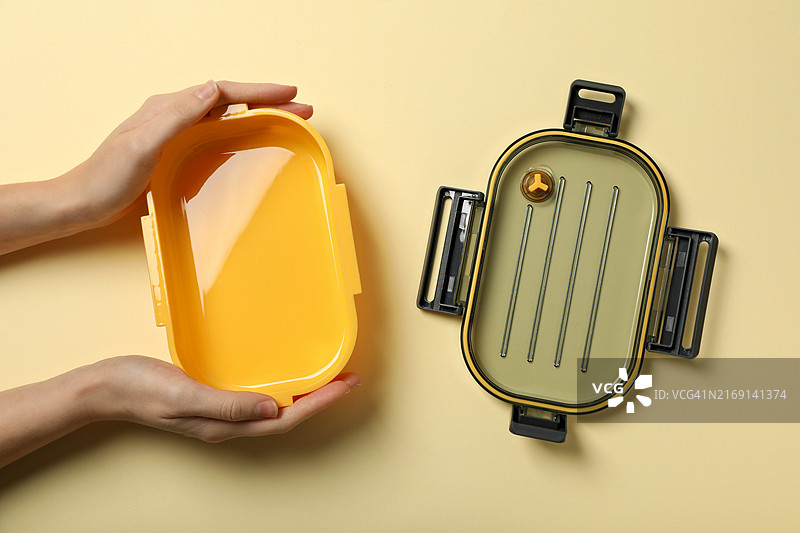 女子手持黄色回收箱的局部特写图片素材