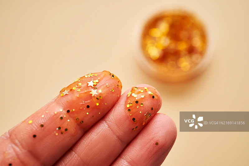 彩色背景上手拿彩色星星糖果的手部特写图片素材