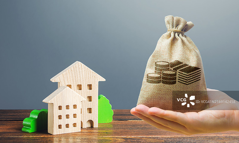 在灰色背景下手持带有纸币和硬币的房屋模型的局部照片图片素材