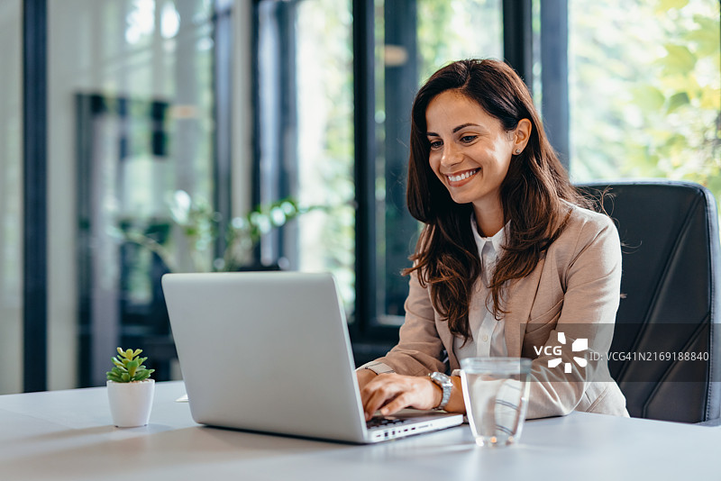 在现代办公室里使用笔记本电脑的职业女性图片素材
