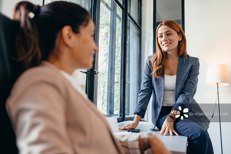两位有魅力的女商人坐在办公桌旁讨论项目图片素材