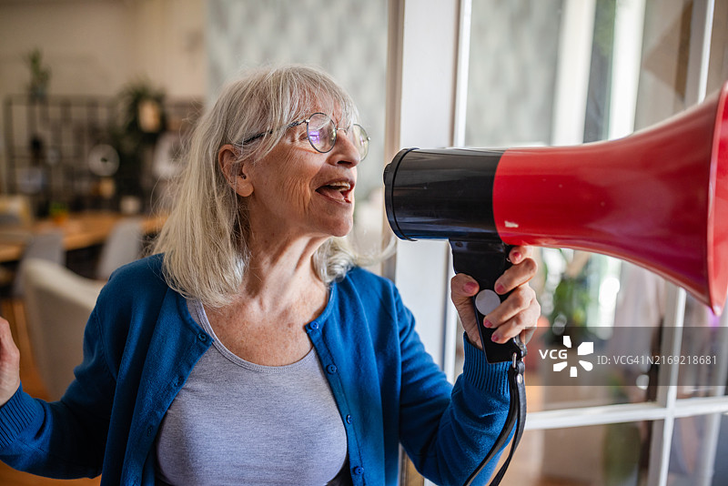 女人在明亮的房间里拿着红色扩音器图片素材