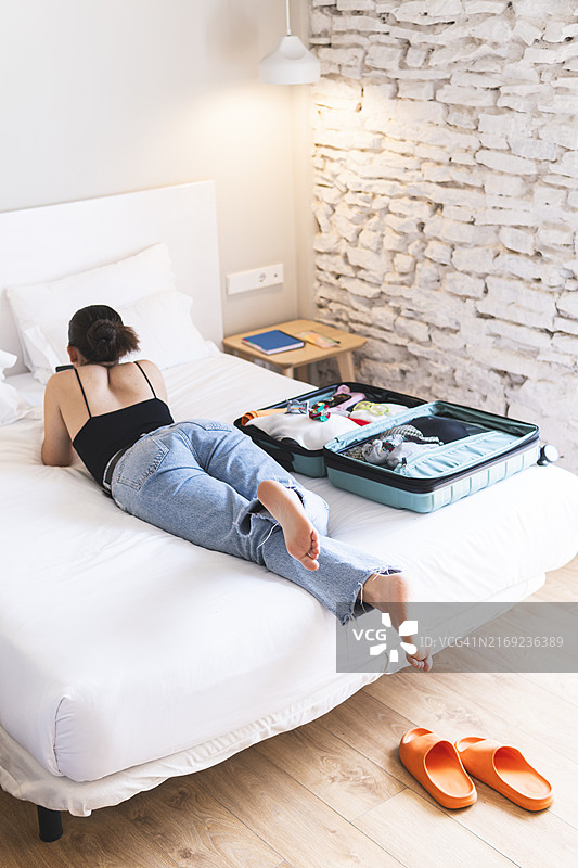 在酒店房间里用手机躺在床上的女人图片素材