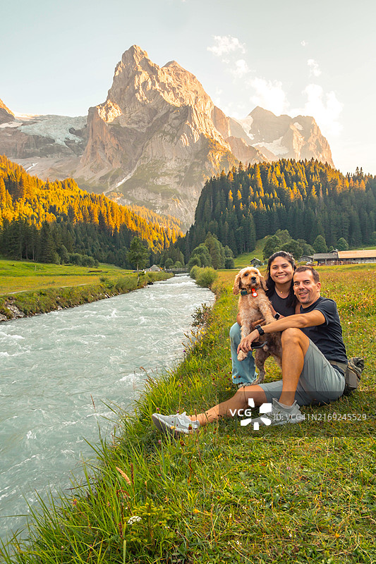 情侣带狗在瑞士阿尔卑斯山旅行，欣赏壮丽景色图片素材