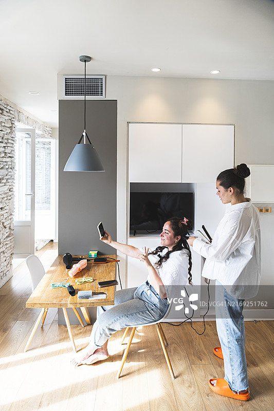 女人在家为朋友卷发自拍图片素材