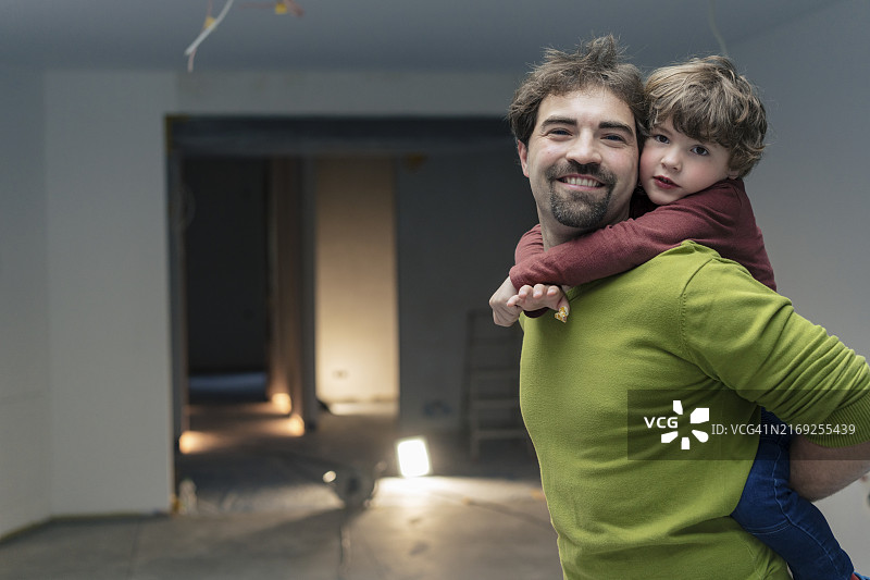 父亲背着儿子站在新公寓里图片素材