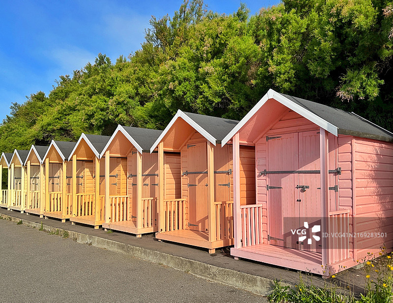 英国肯特郡福克斯通海滨长廊上的一排彩色木制海滩小屋图片素材