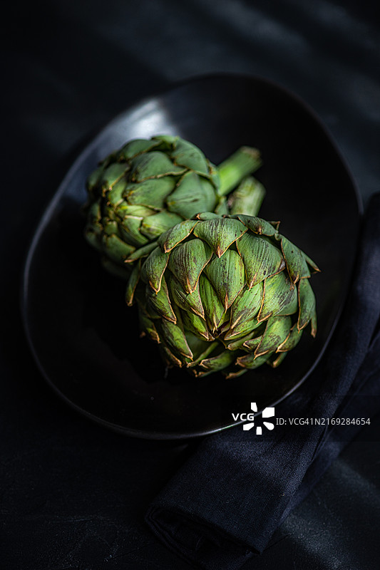 阴影中，放在锡盘上的两颗朝鲜蓟特写图片素材