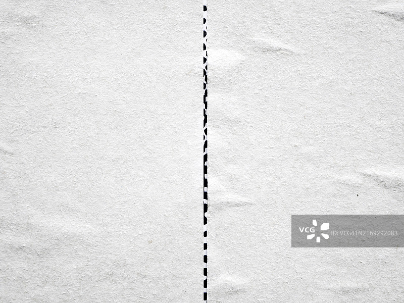 两张白色、有纹理和褶皱的海报贴在墙上特写。海报下方可以看到另一张黑白海报。无标志或商标。自然光和颜色。比利时布鲁塞尔。图片素材