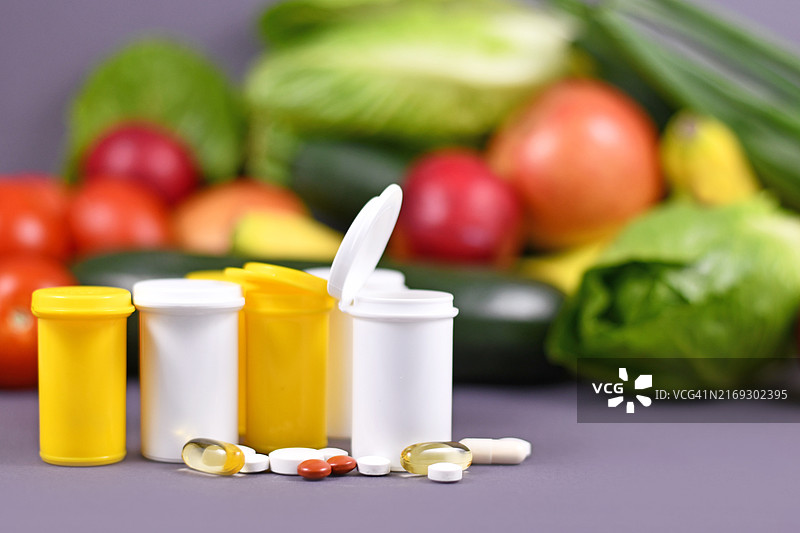 水果蔬菜背景下的食品营养补充药丸瓶图片素材