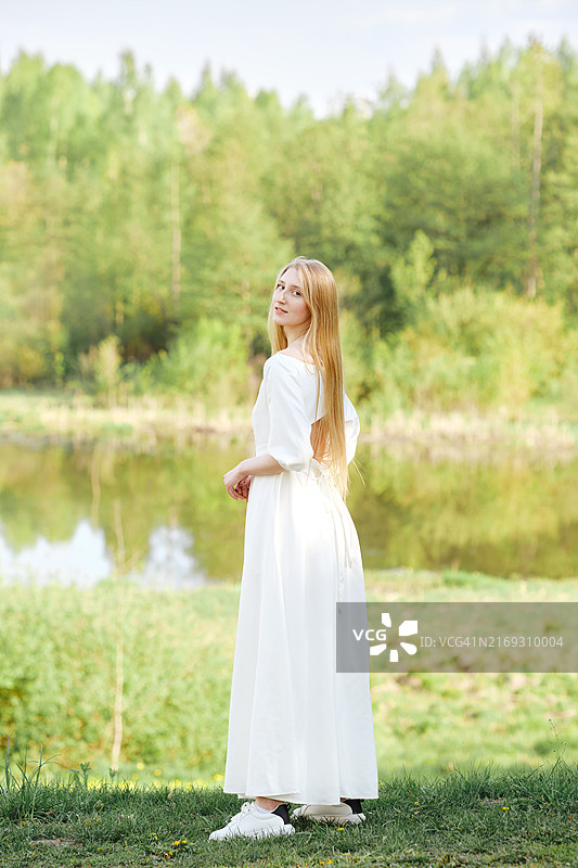 身穿白色长裙的年轻女子在河岸边的全身像图片素材
