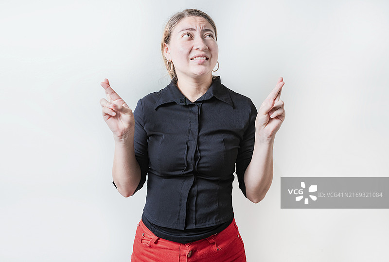 许愿的忧虑年轻女人。交叉手指许愿的美丽女孩图片素材