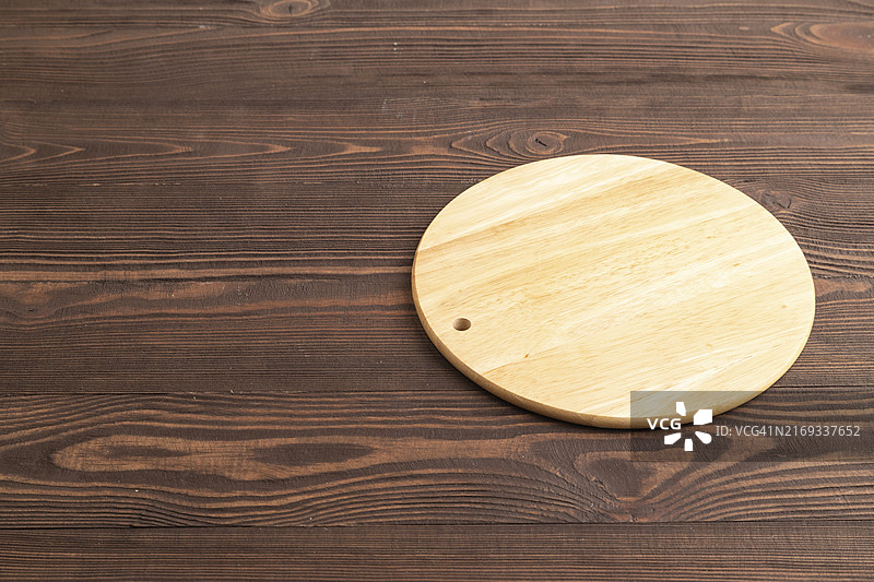 棕色木质背景上的圆形木制砧板，侧视图，留白区域图片素材