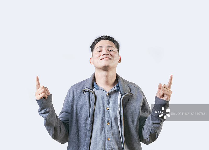 快乐的男人指向上方的广告，年轻人指着空白处并对着镜头微笑图片素材