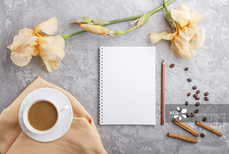 灰色背景上的橙色鸢尾花和咖啡杯笔记本图片素材