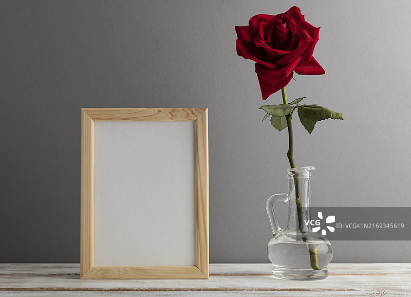 灰色纸背景上的玻璃红玫瑰白色木制相框样机图片素材