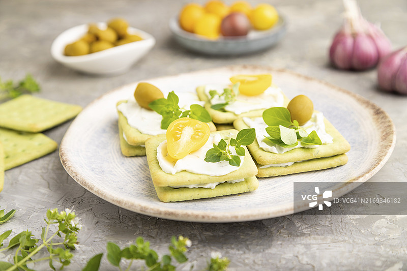 灰色水泥背景上的奶油奶酪和樱桃番茄绿色饼干三明治，侧视图，特写，选择性聚焦图片素材