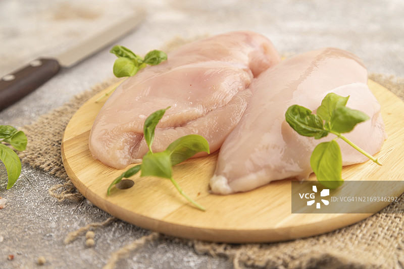棕色水泥背景木制砧板上带香草和香料的生鸡胸肉，侧视图，特写，选择性聚焦图片素材