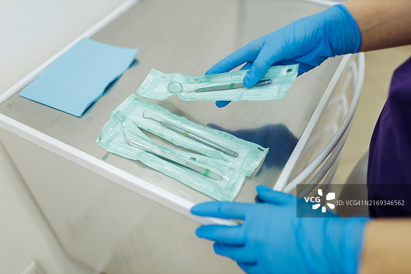 戴蓝色外科手套的女牙医擦拭牙科设备图片素材