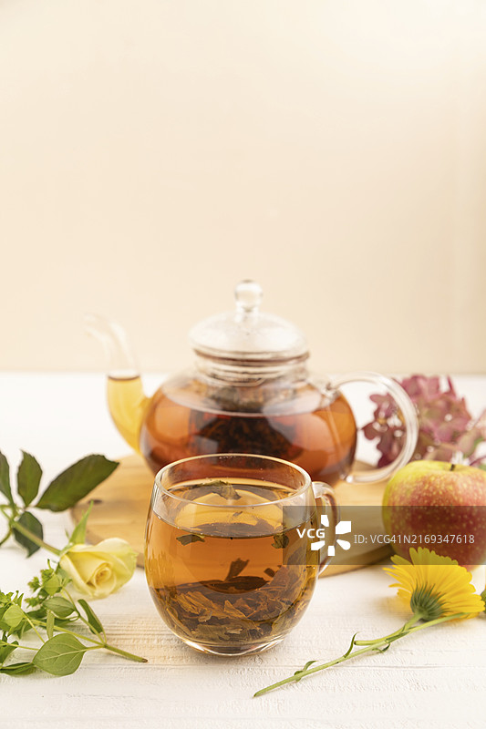 白色木质背景玻璃茶壶中的草药红茶，健康饮品概念图片素材