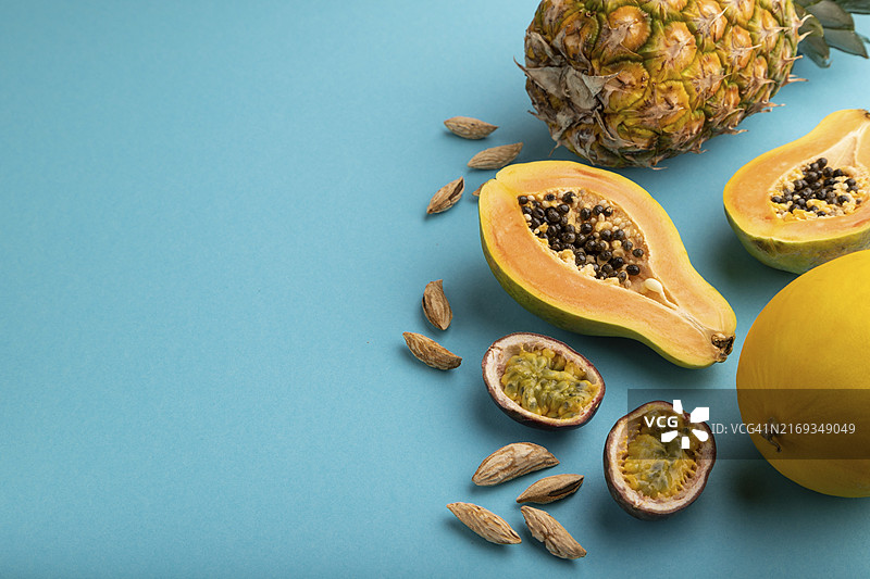 成熟的切开的木瓜、菠萝、甜瓜、百香果、杏仁，在蓝色背景上图片素材