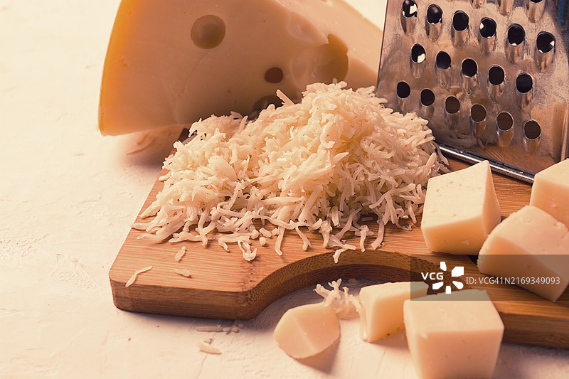 砧板上的马斯丹碎奶酪、磨碎器和奶酪刀，特写图片素材