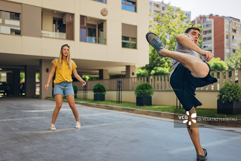 男女在建筑物前用脚玩毽子图片素材