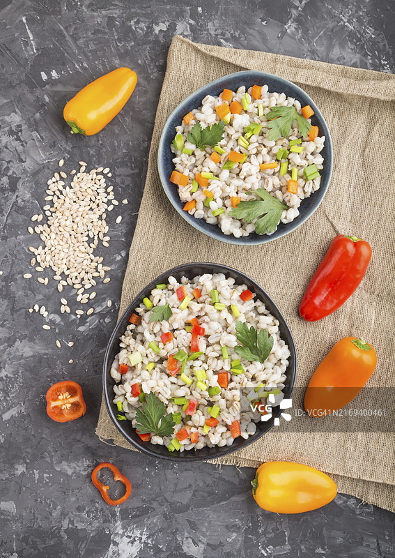 蓝色陶瓷碗中配蔬菜的珍珠大麦粥，黑色混凝土背景和亚麻纺织品，顶部视图，平铺，特写，俄罗斯传统美食图片素材