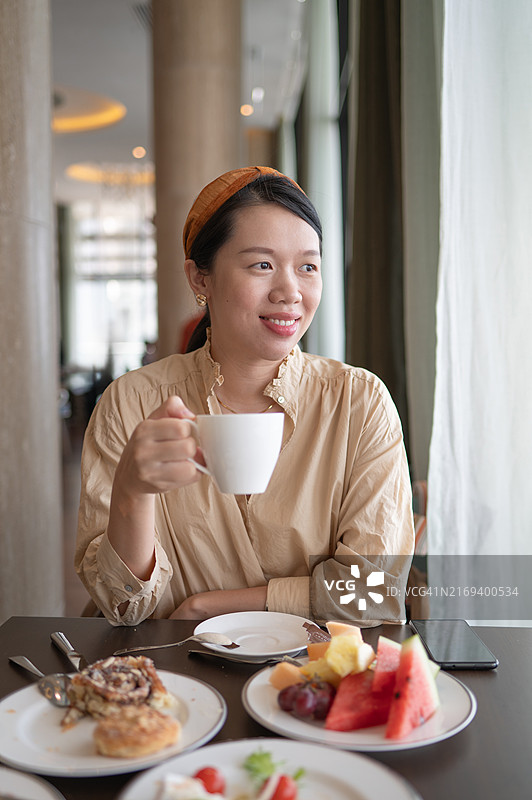 女人在餐厅窗边享用早餐咖啡图片素材