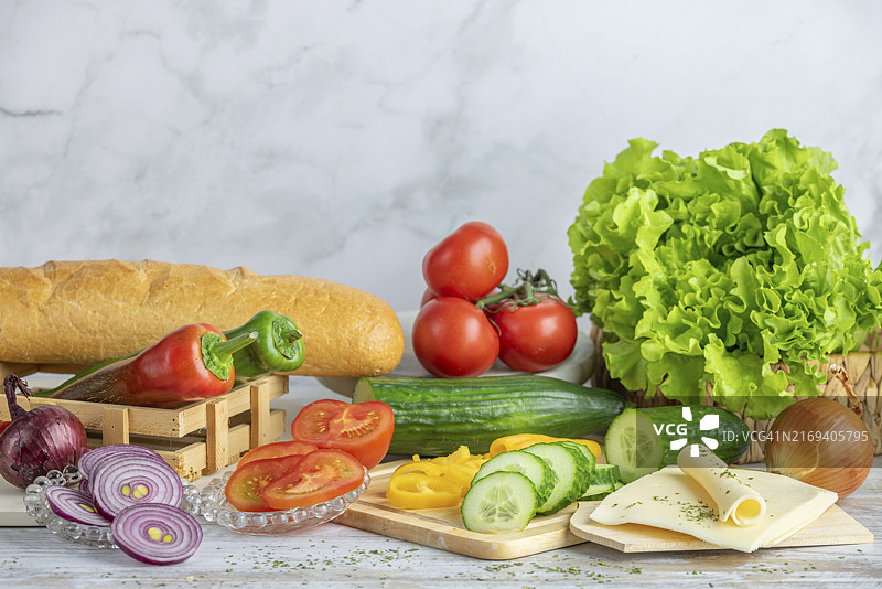 彩色辣椒、西红柿和黄瓜与法棍面包沙拉和奶酪片图片素材