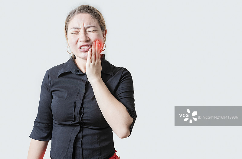 牙痛的年轻女人。不快乐的女孩揉着脸颊图片素材