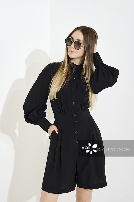 身穿黑色衬衫和短裙，抚摸柔顺长发的开朗年轻女子图片素材