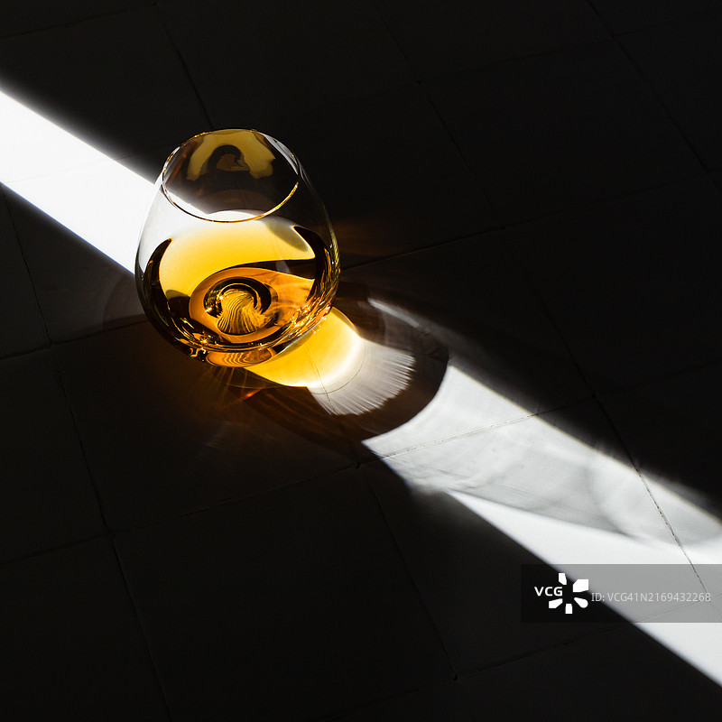 白色背景下具有强烈光影效果的玻璃杯威士忌图片素材