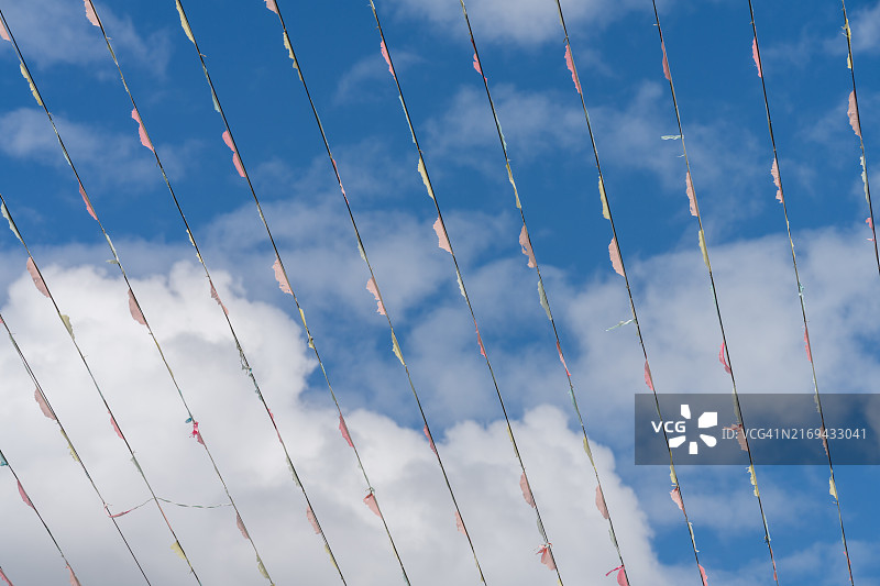 湛蓝天空下的彩色三角旗和云朵图片素材